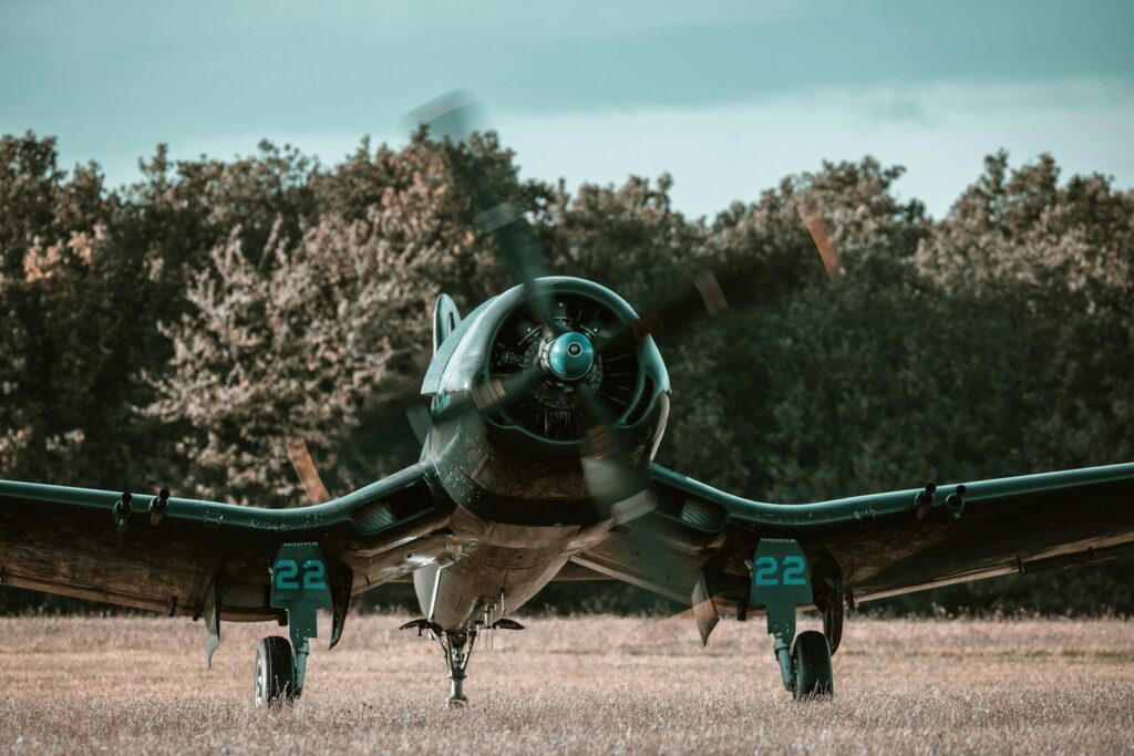 Vintage airplane with spinning propeller on grassy airfield.