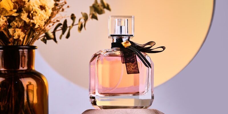 Photo by Ryan Lu a bottle of perfume next to a vase with flowers