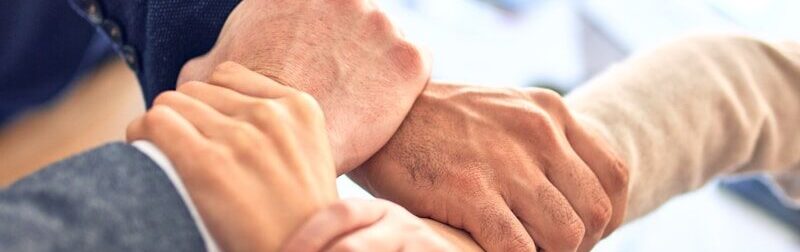 team members gripping wrists in unity gesture