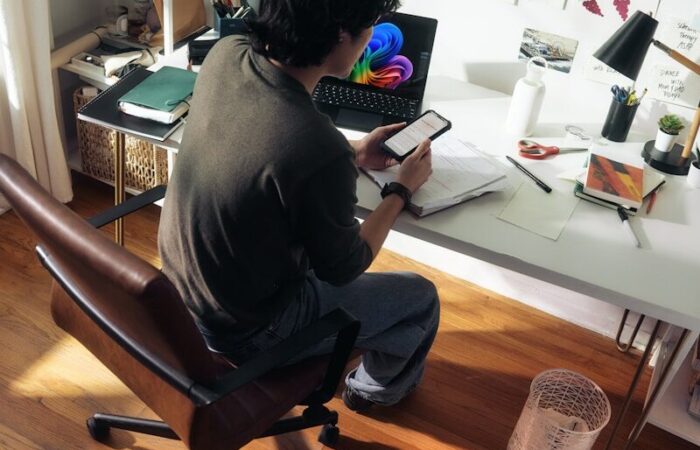 Man working at desk with laptop and phone.