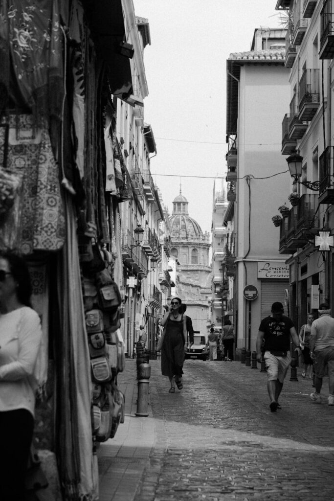 A black and white photo of people walking down a street
