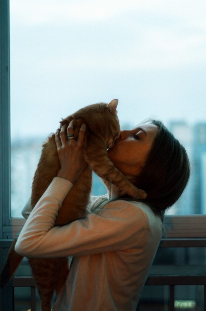 a woman holding a cat up to her face